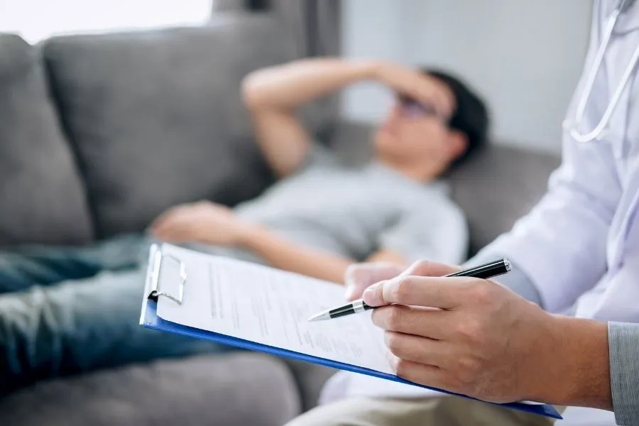 Специалист, работающий за ноутбуком на фоне окна, за которым виден город и небо